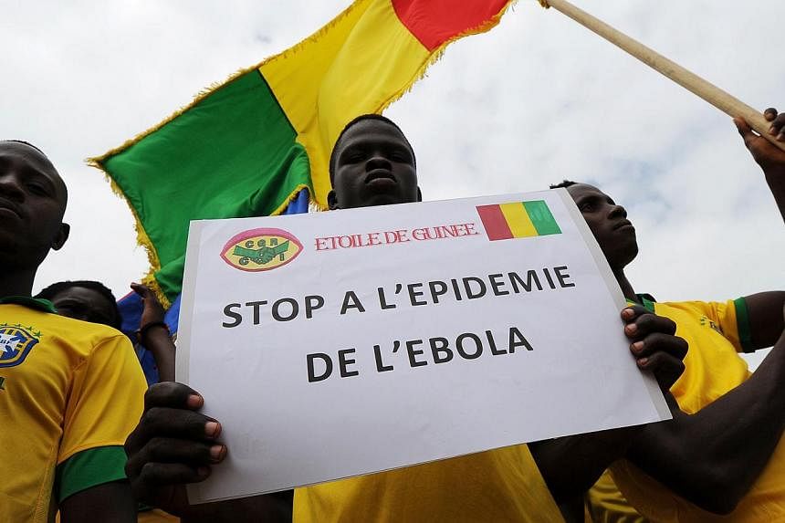 Players of the '"L'Etoile de Guinee" football team pose with a sign reading ''Stop the ebola epidemic'' prior to a football tournament gathering youth from Guinea near the Koumassi sports centre in Abidjan on August 10, 2014. The &nbsp;West African E
