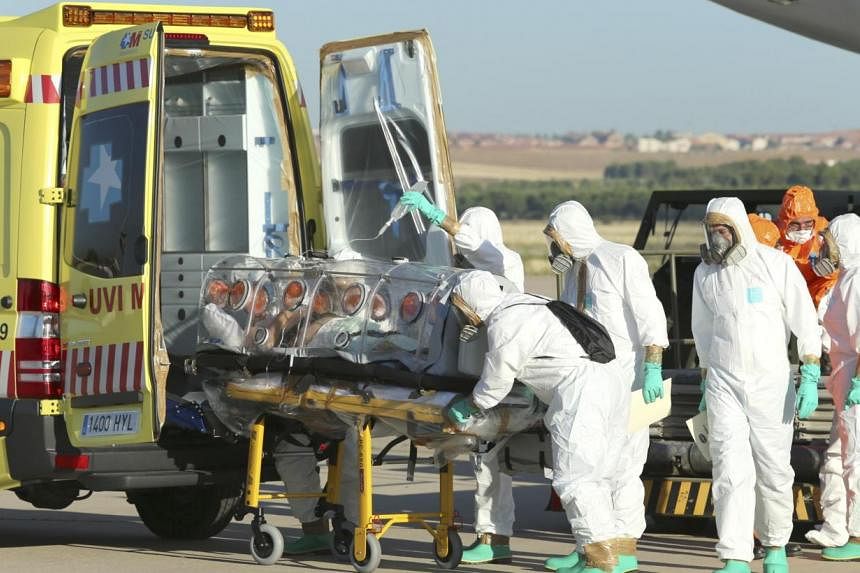 Health workers put Ebola patient, Spanish priest Miguel Pajares, into an ambulance on the tarmac of Torrejon airbase in Madrid, after he was repatriated from Liberia for treatment in Spain. Should we worry if a Singaporean gets infected? -- PHOTO: RE