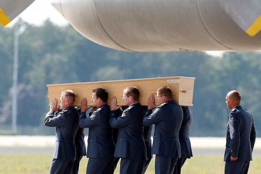 Men carry a coffin containing human remains collected over the last couple of days at the crash site of Malaysia Airlines flight MH17 in Ukraine, upon its arrival at the Eindhoven Airport, the Netherlands on Aug 4, 2014. -- PHOTO: AFP&nbsp;