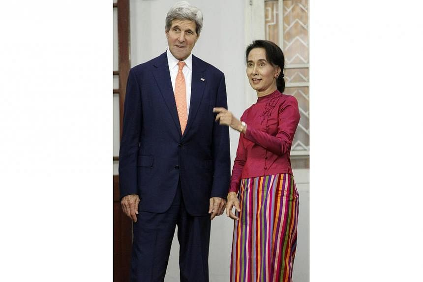 US Secretary of State John Kerry stands next to Myanmar opposition leader Aung San Suu Kyi as she gestures during a photo session before their meeting at her residence in Yangon on Aug 10, 2014.&nbsp;-- PHOTO: REUTERS