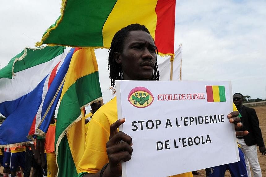 Players of the ''L'Etoile de Guinee'' football team pose with a sign reading ''Stop to the ebola epidemic'' prior to a football tournament gathering youth from Guinea near the Koumassi sports center in Abidjan on Aug 10, 2014.&nbsp;As the world scram