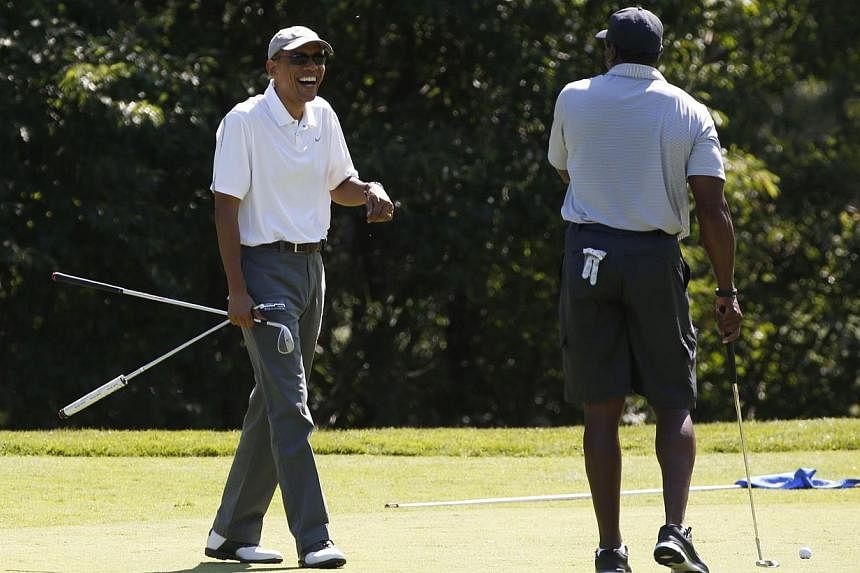 Mr Obama laughs with former NFL star Ahmad Rashad (right) while playing a round of golf on Martha's Vineyard in Massachusetts August 9, 2014, where his family is taking a two-week vacation. The scene contrasted with his earlier statement from the Whi
