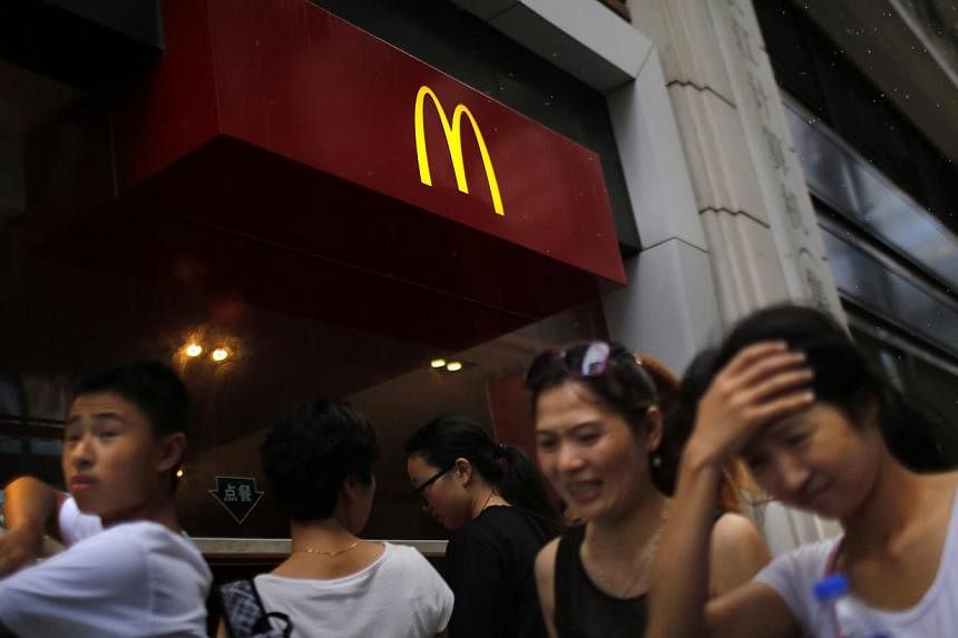 People walk by a McDonald's store in downtown Shanghai on July 31, 2014.&nbsp;Five fast food chains including McDonald's and Yum Brands Inc have published details of their suppliers on their Chinese websites following a request from Shanghai authorit