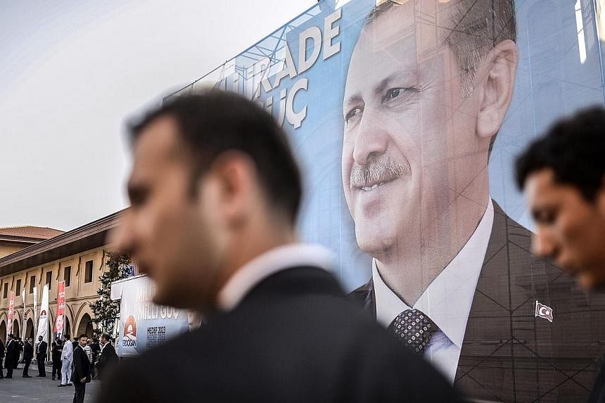 Security officers wait in front of a giant poster bearing a picture of Turkish prime minister and presidential candidate Recep Tayyip Erdogan on August 10, 2014, in Istanbul. Mr Erdogan won Turkey’s first popular presidential election on Sunday wit