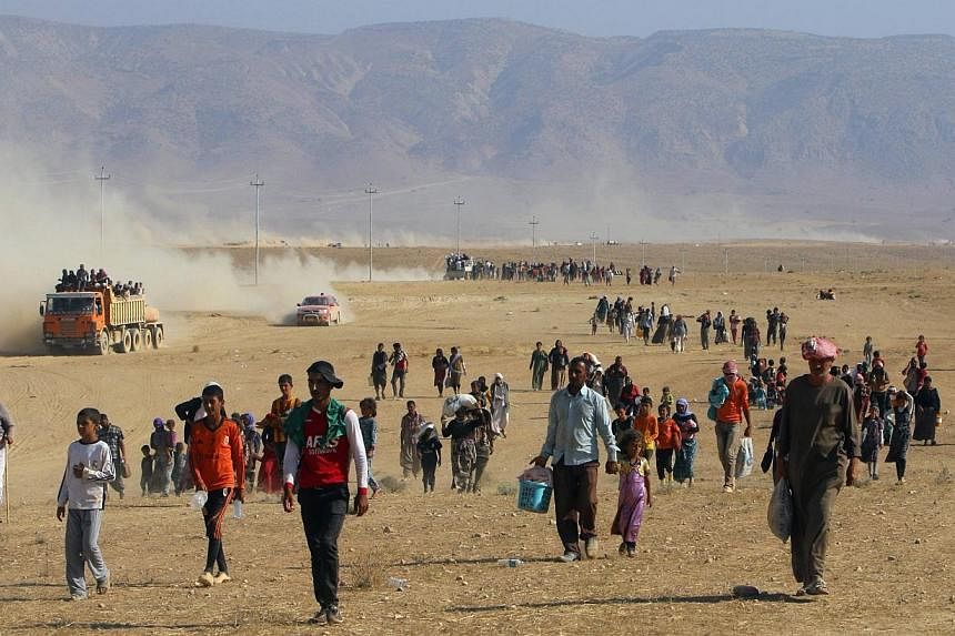 Displaced people from the minority Yezidi sect, fleeing violence from forces loyal to the Islamic State in Sinjar town, walk towards the Syrian border, on the outskirts of Sinjar mountain, near the Syrian border town of Elierbeh of Al-Hasakah Governo