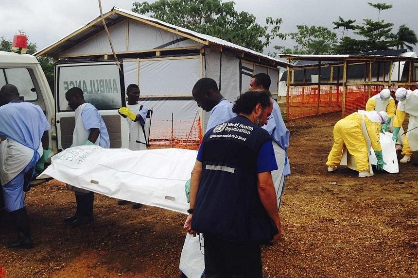 Volunteers carry bodies in a centre run by Medecins Sans Frontieres for Ebola patients in Kailahun on Aug 2, 2014. -- PHOTO: REUTERS