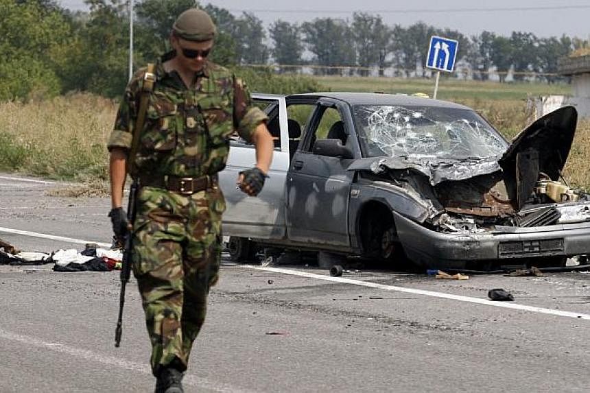 A Ukrainian soldier walks past a damaged car which was used by pro-Russian militants who tried to break through the checkpoint of Ukrainian forces, near the eastern Ukrainian city of Donetsk on August 11, 2014. With Ukraine reporting Russia has masse