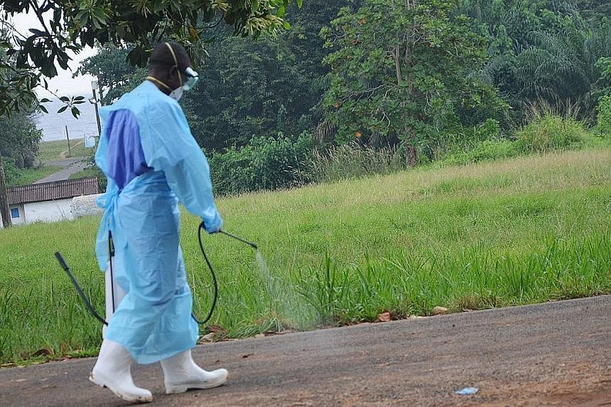 A file photo taken on July 24, 2014 shows a staff member of the Christian charity Samaritan's Purse spraying product as he treats the premises outside the ELWA hospital in the Liberian capital Monrovia. Japan's foreign aid agency said on Tuesday. Aug