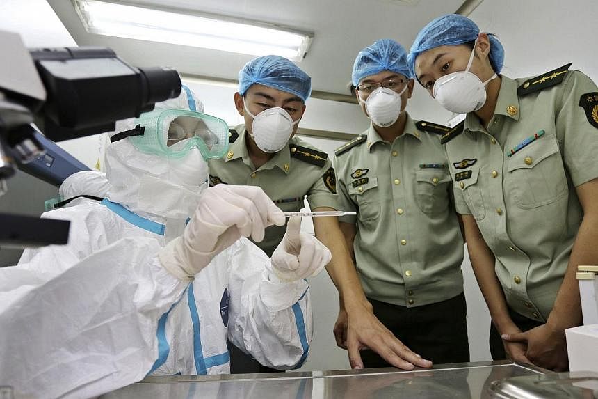 A health inspection and quarantine researcher (left) demonstrating to customs policemen the symptoms of Ebola, at a laboratory at an airport in Qingdao, in China's Shandong province on August 11, 2014. China's quarantine authority has ordered stepped