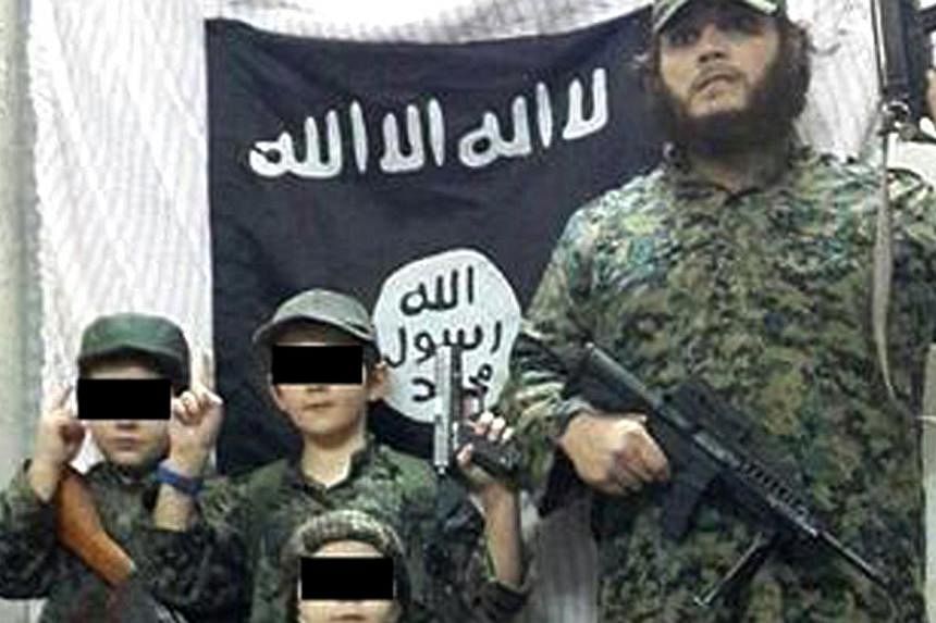 Khaled Sharrouf and boys believed to be his sons stand in front of the Islamic State flag. -- PHOTO: TWITTER