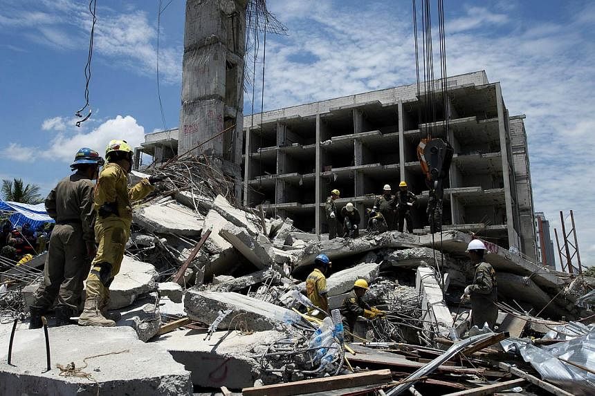 Thai rescue workers use cranes to search for trapped people after a six-storey building under construction collapsed in Pathum Thani province on Aug 12, 2014.&nbsp;Thai rescuers Tuesday pulled a survivor from the rubble of a collapsed building as the