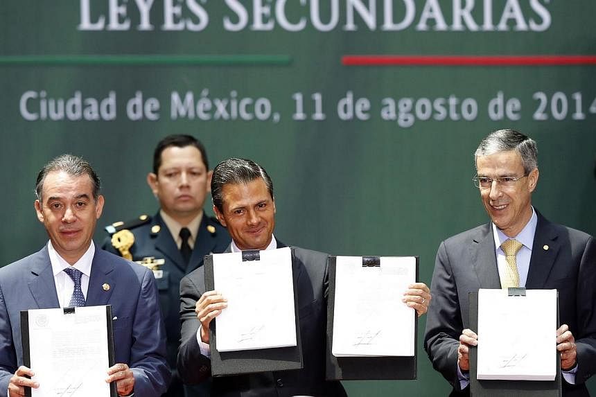 Mexico's President Enrique Pena Nieto (centre), the president of Mexico's Senate Raul Cervantes (left) and president of the Chamber of Deputies Jose Gonzalez hold up a written version of an energy reform at the National Palace in Mexico City August 1
