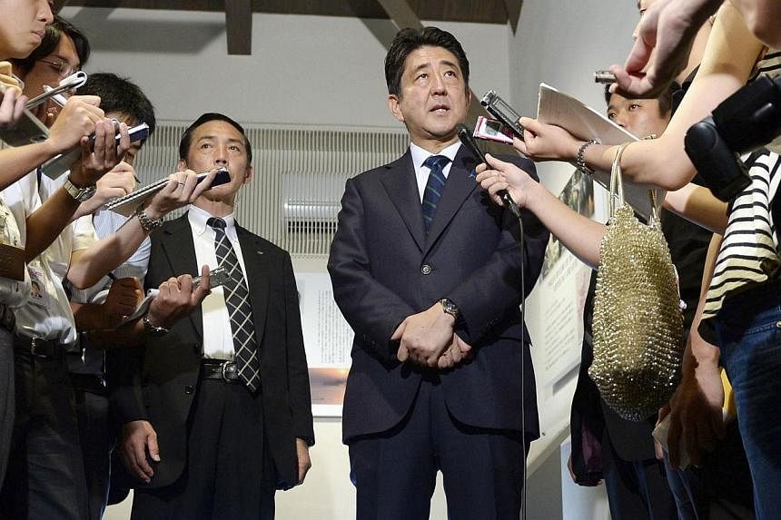 Japan's Prime Minister Shinzo Abe speaks to the media after visiting a shopping street in Shimonoseki, western Japan, in this photo taken by Kyodo August 13, 2014.&nbsp;Japan will lodge a "strong protest" with Russia over military exercises reportedl