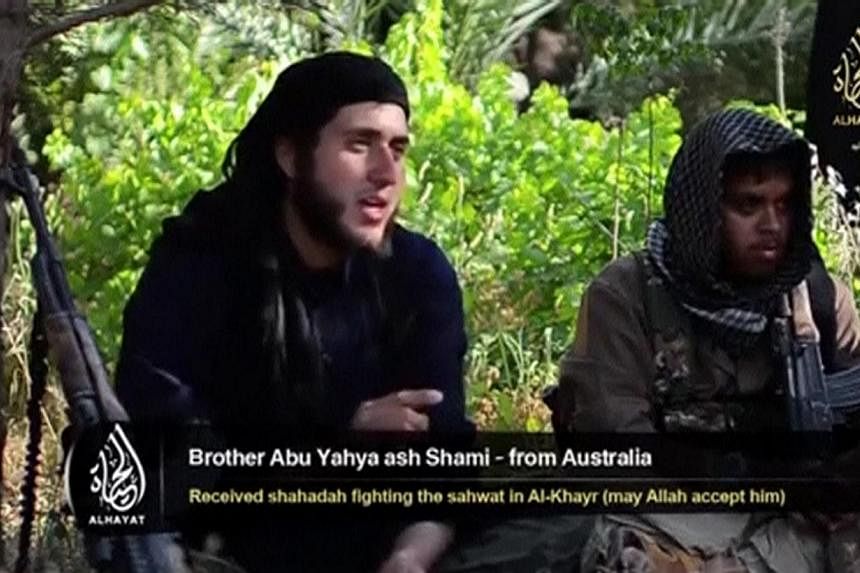 An Islamist fighter, identified as Abu Yahya al-Shami from Australia (left), speaks in this still image taken undated video shot at an unknown location. Australians are becoming key players in the successful "social media wars" being waged from Iraq 
