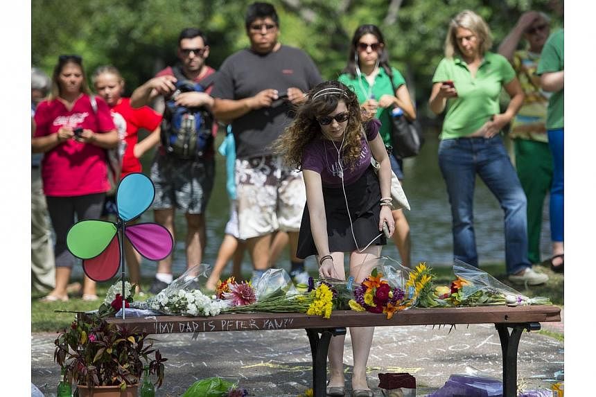 Annie Hochheiser of Cambridge, Massachusetts places flowers onto a fan memorial in honour of Robin Williams on the bench made famous by his movie Good Will Hunting in Boston Public Garden on August 12, 2014 in Boston, Massachusetts. Williams died in 