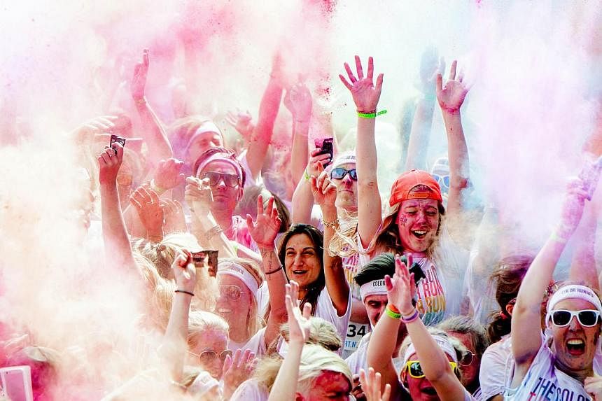 Participants of the Color Run throw powder in the air in Amsterdam, The Netherlands, on May 31, 2014. If survey data is to be trusted, there's a surprisingly weak relationship between money and happiness. As national incomes rise, happiness does not 