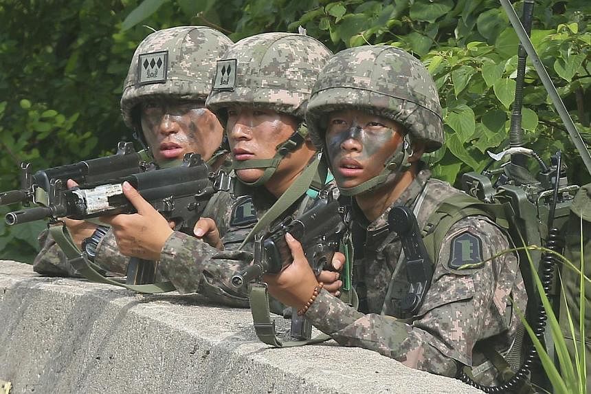 South Korean soldiers take position during a search and arrest operation as troops standoff with a conscript soldier who shot and killed five comrades in Goseong on June 23, 2014. South Korea's military outlined measures on August 13, 2014, to curb b