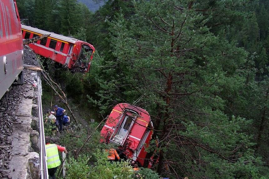 Police and rescue workers help after a passenger train derailed into a ravine near the village of Tiefencastel in a mountainous region of southeastern Switzerland after encountering a mudslide on the tracks on August 13, 2014. Several passengers were