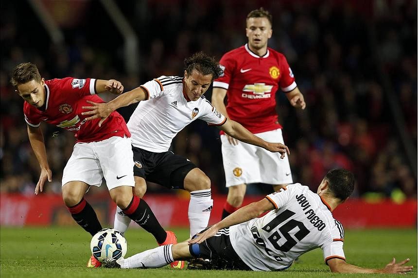 Valencia's Andres Guardado (centre) and Javi Fuego (bottom) challenge Manchester United's Adnan Januzaj (left) during their friendly soccer match at Old Trafford in Manchester, northern England August 12, 2014. -- PHOTO: REUTERS