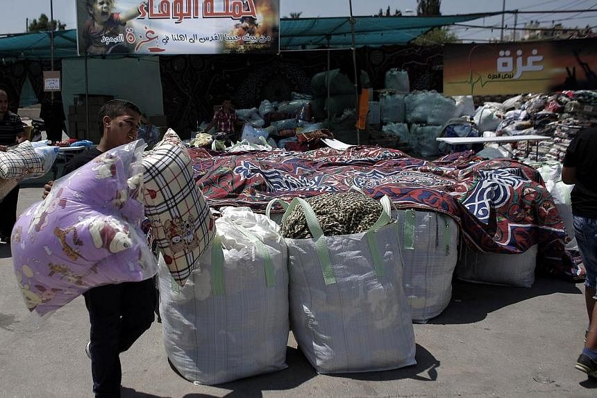 Palestinians collect goods and blankets in East Jerusalem, on Thursday, Aug 14, 2014, to be sent and distributed with the Red Cross to people in need in the Gaza Strip.&nbsp;A new, five-day truce between Israel and Hamas appeared to be holding on Thu