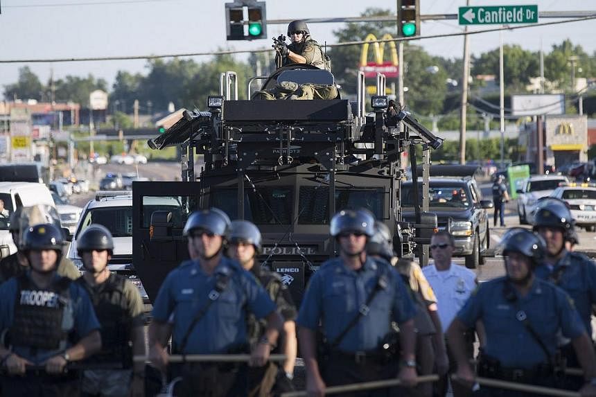 Riot police stand guard as demonstrators protest the shooting death of teenager Michael Brown in Ferguson, Missouri on Aug 13, 2014.&nbsp;Police in Ferguson, Missouri, fired tear gas, stun grenades and smoke bombs, to disperse some 350 protesters lat