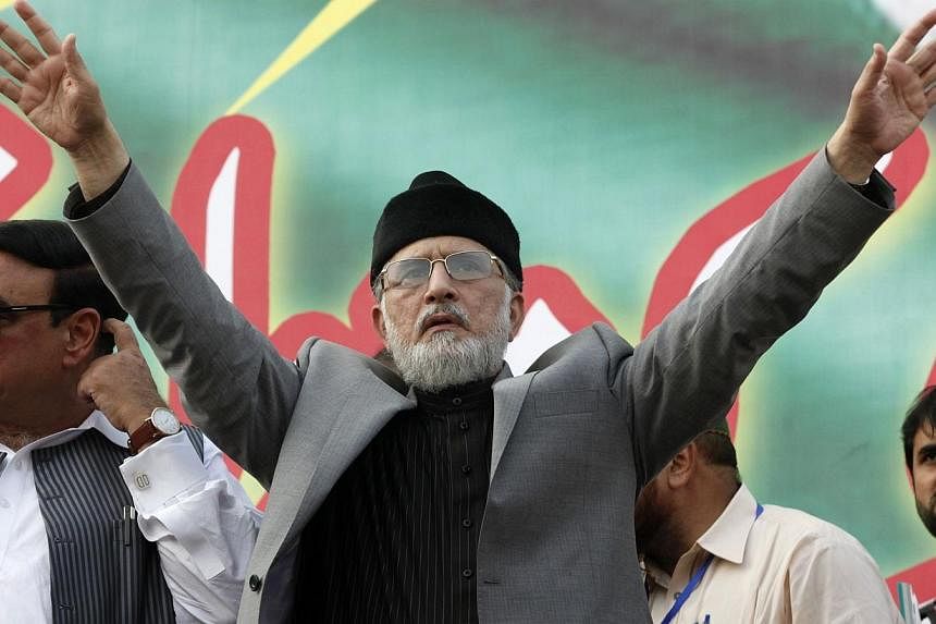 Muhammad Tahir ul-Qadri, Sufi cleric and leader of political party Pakistan Awami Tehreek (PAT), gestures to supporters during a demonstration outside his residence in Lahore on Aug 10, 2014. -- PHOTO: REUTERS