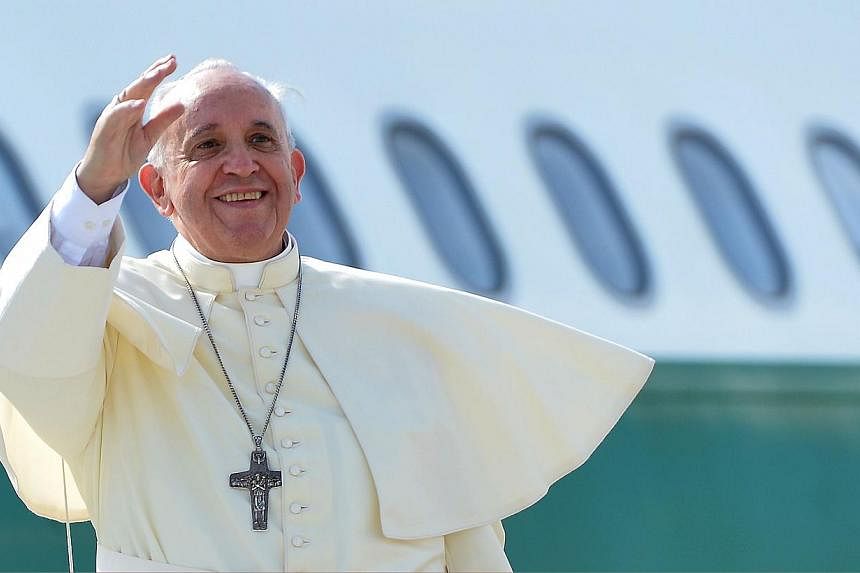 Pope Francis waves from the top of the stairs leading to the plane that will carry him to the South Korea, at Rome's Fiumicino international airport on Aug 13, 2014. -- PHOTO: AFP