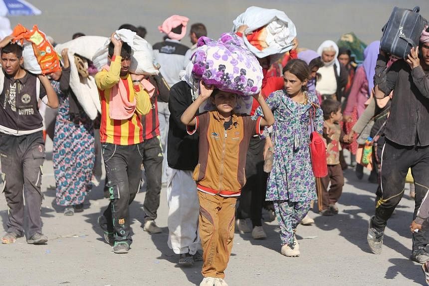 Displaced Iraqi families from the Yazidi community cross the Iraqi-Syrian border at the Fishkhabur crossing, in northern Iraq, on Aug 13, 2014. -- PHOTO: AFP