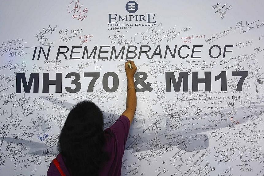 A woman writes a message on a dedication board for the victims of the downed Malaysia Airlines Flight MH17 airliner and the missing Flight MH370, in Subang Jaya outside Kuala Lumpur on July 23, 2014. -- PHOTO: REUTERS