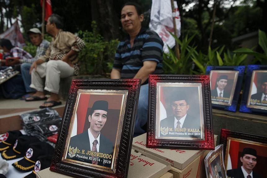A vendor selling portraits of President-elect Joko Widodo and his running mate Jusuf Kalla in Jakarta after last month’s election. Expectations are high that Mr Joko will be able to peacefully push through necessary reforms. -- PHOTO: REUTERS