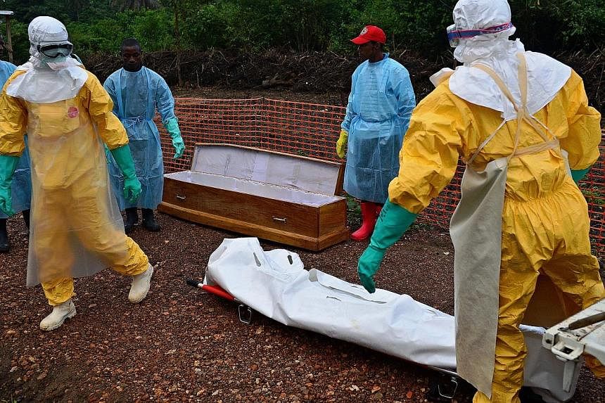 Medicins Sans Frontieres (MSF) medical workers wearing protective clothing carry the body bag of an Ebola victim at the MSF facility in Kailahun, on Aug 14, 2014.&nbsp;Staff with the World Health Organisation battling an Ebola outbreak in West Africa