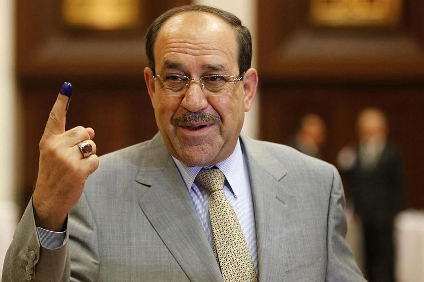 Iraq's Prime Minister Nouri al-Maliki shows his ink marked finger as he votes during parliamentary election in Baghdad in this April 30, 2014 file photo. Maliki has given up his fight to remain prime minister of Iraq and now supports his replacement,