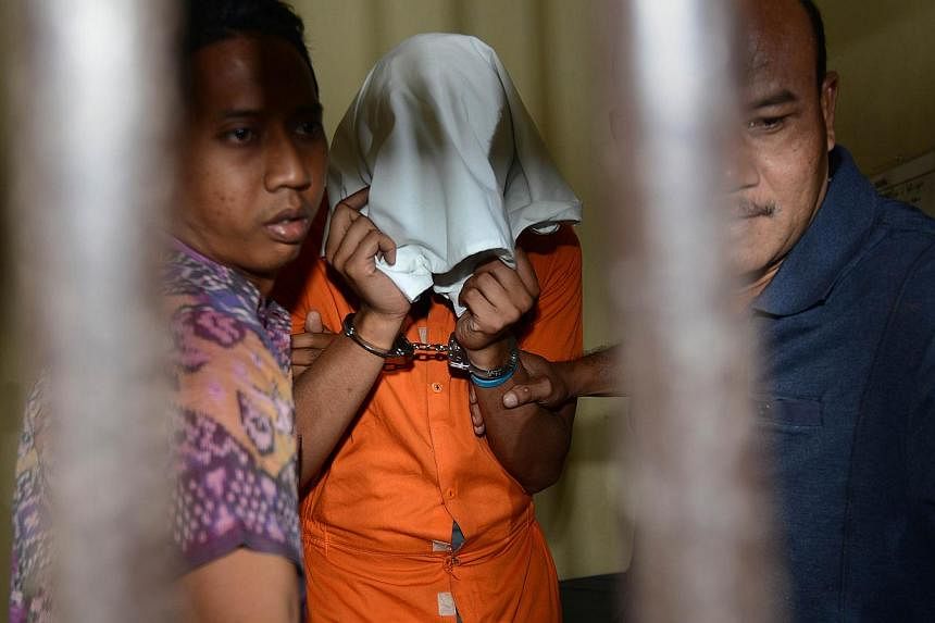 Police escort suspect Tommy Schaefer&nbsp;(centre), suspected in the murder of Sheila von Wiese Mack, while in custody at a holding cell at Bali police hospital in Denpasar on the Indonesian resort island of Bali on Aug 15, 2014. -- PHOTO: AFP