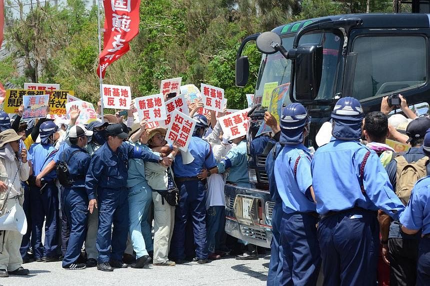 Protesters stage a rally at the gates of Camp Schwab, near the site of the new US military runways in Nago, Okinawa prefecture on August 14, 2014. Anti-military protesters rallied on and off shore on August 14 as work began as part of the long-stalle