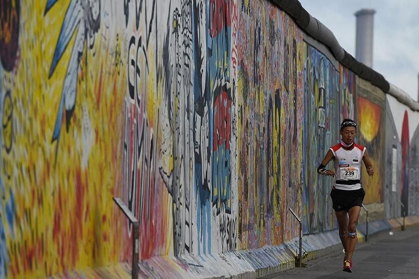 Runners pass the former Berlin Wall during the "100 Meilen Berlin 2014" marathon event in Berlin on Aug 16, 2014.&nbsp;Around 300 runners left the starting gate Saturday for an ultramarathon tracing the route of the Berlin Wall, marking 25 years sinc