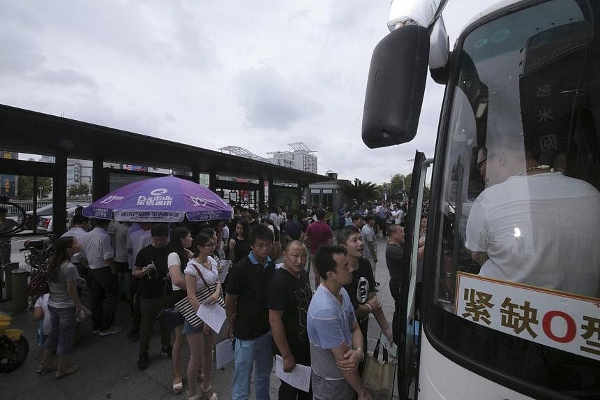 People line up in front of a bus to donate blood for the victims of an explosion at a factory in Kunshan, Jiangsu province on Aug 2, 2014.&nbsp;Police arrested seven people in north-west China allegedly involved in a scheme that forced school childre
