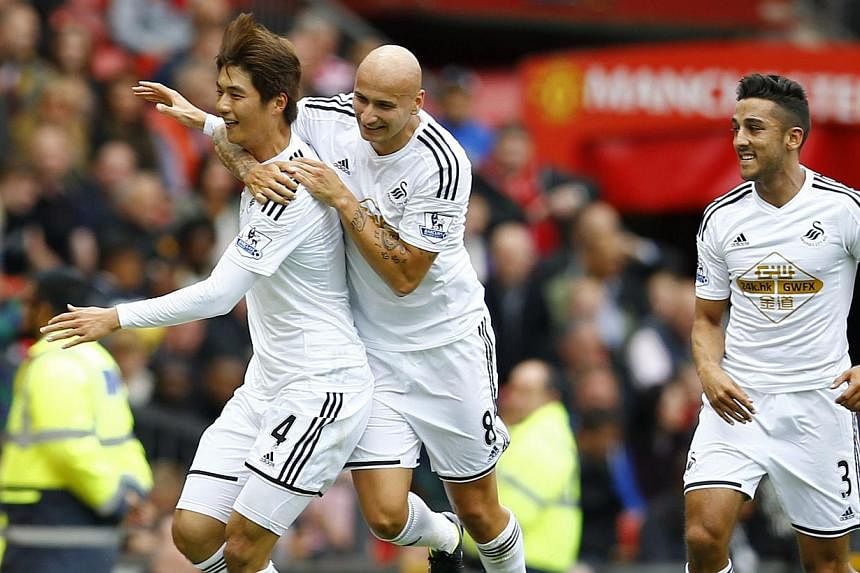 Swansea City's Ki Sung Yueng (left) celebrates with teammates Jonjo Shelvey (centre) and Neil Taylor after scoring a goal against Manchester United during their English Premier League match at Old Trafford on Aug 16, 2014. -- PHOTO: REUTERS