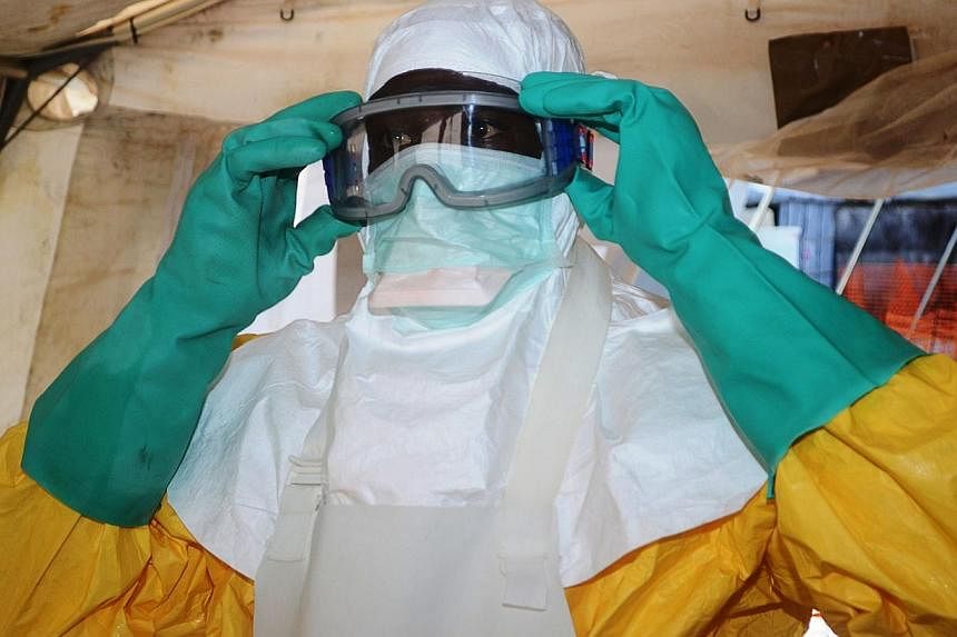 A file photo taken on June 28, 2014 shows a member of Doctors Without Borders (MSF) putting on protective gear at the isolation ward of the Donka Hospital in Conakry, where people infected with the Ebola virus are being treated.&nbsp;The Ebola epidem