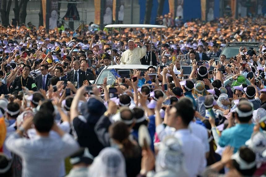Catholic worshippers wave as Pope Francis (centre) arrives at Gwanghwamun Square in central Seoul on Aug 16, 2014. A&nbsp;&nbsp;tight security cordon was thrown around central Seoul on Saturday to screen out possible threats as up to one million peop