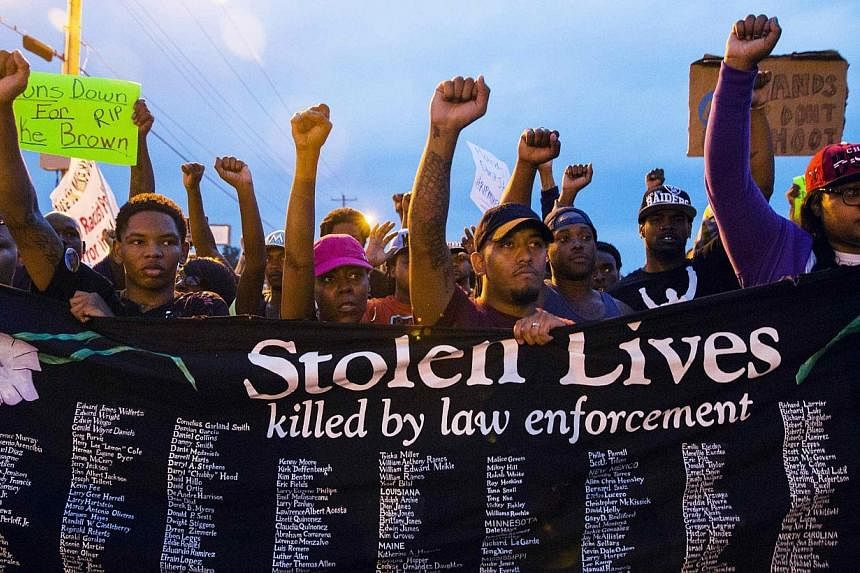 Protestors march and hold their fists aloft during ongoing demonstrations in reaction to the shooting of Michael Brown in Ferguson, Missouri August 16, 2014.&nbsp;-- PHOTO: REUTERS