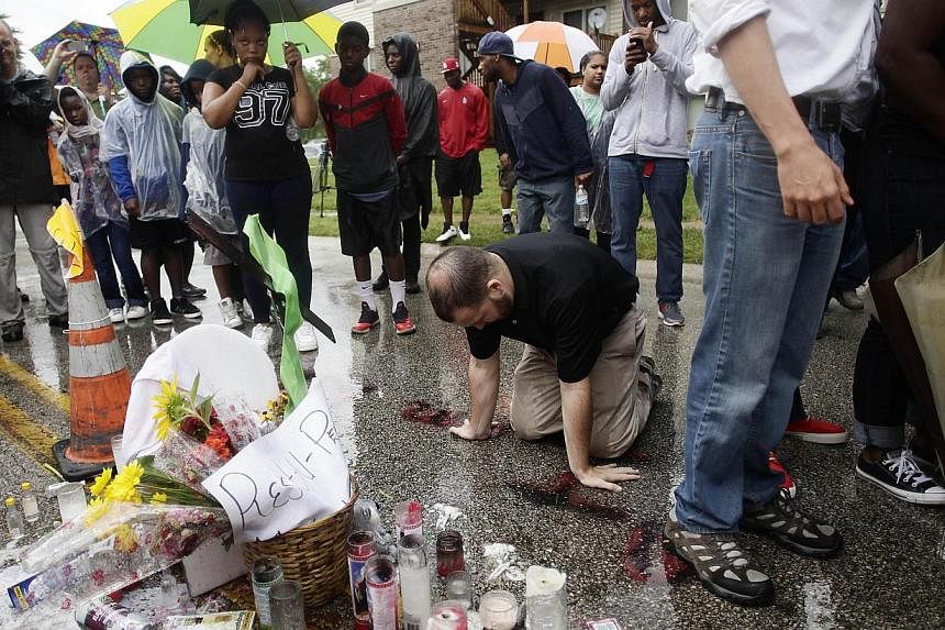 A man kneels and prays at a makeshift memorial at the location where 18-year-old Michael Brown was killed on Canfield Drive in Ferguson, Missouri, on Aug 16, 2014. -- PHOTO: AFP