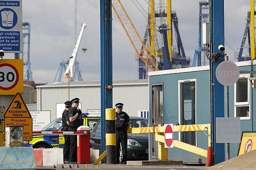 Police stand guard at an entrance to Tilbury Docks, east of London, on August 16, 2014, where one man was found dead and 34 men, women and children were found to be suffering from severe dehydration and hypothermia. Officers on Sunday said those in t