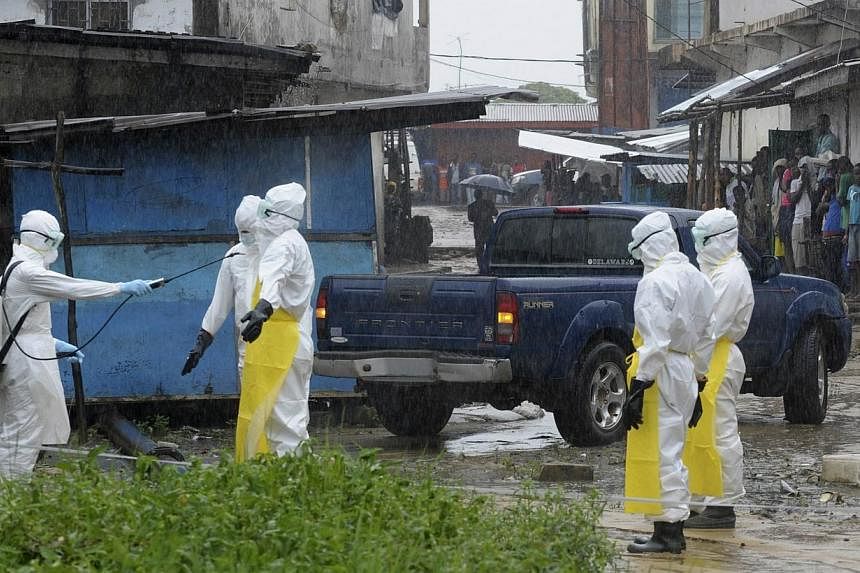 Health workers wearing protective clothing disinfect themselves after an abandoned dead body presenting with Ebola symptoms was found at Duwala market in Monrovia on Aug 17, 2014.&nbsp;Liberian officials were searching on Monday, Aug 18, for 17 Ebola