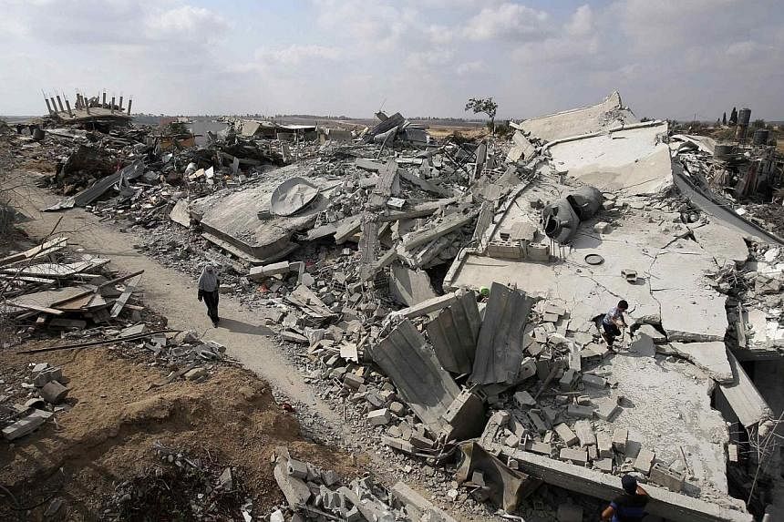 A Palestinian woman walks past the ruins of houses which witnesses said were destroyed during the Israeli offensive in Johr El-Deek village near the central Gaza Strip on Aug 17, 2014.&nbsp;The death toll in the war-torn Gaza Strip rose above 2,000 o