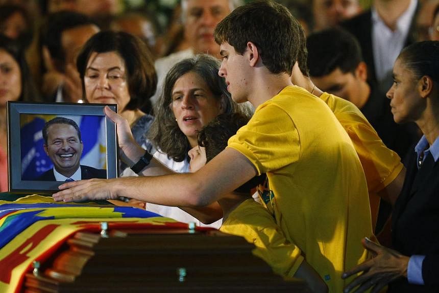 Renata Campos (fourth from right), wife of the late Brazilian presidential candidate Eduardo Campos, and their children set a picture of the father of five on the coffin containing his remains as his running mate Marina Silva (far right) reacts durin