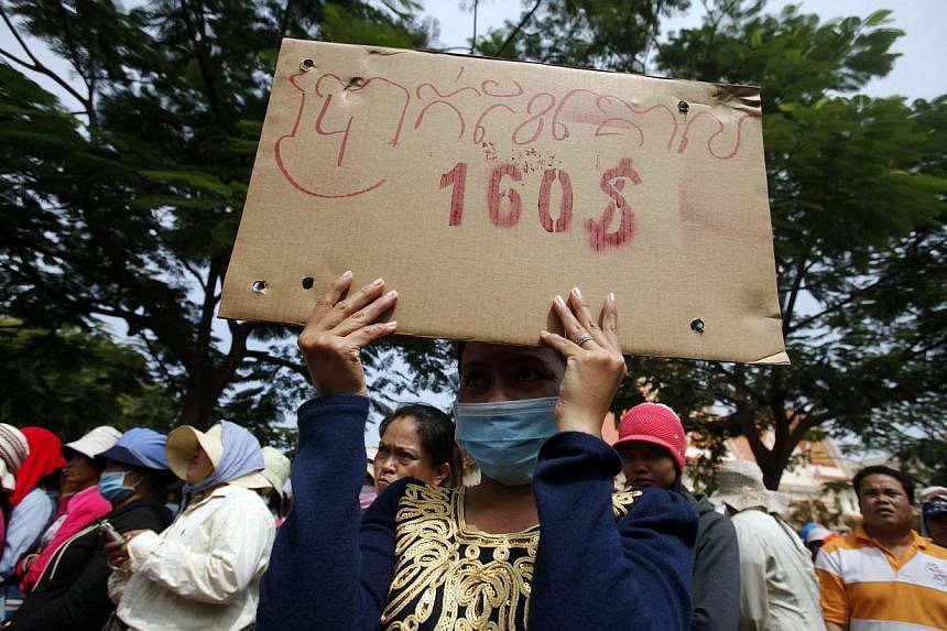 A garment worker holds a placard reading "Monthly minimum wage $160"&nbsp;during a protest in central Phnom Penh in this December 31, 2013 file photo. Labour leaders behind the biggest strikes in Cambodia's US$5 billion (S$6.2 billion)&nbsp;garment i