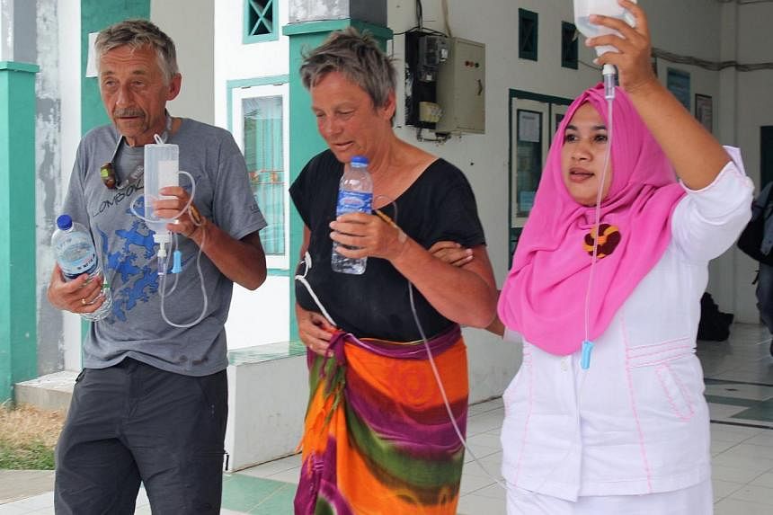 Survivor Jan van Ommen (left) of the Netherlands and fellow Dutch survivor Alice (centre, only first name available) are assisted by a nurse at a hospital in Sape, located on Indonesia's Sumbawa island on August 18, 2014 after being rescued two days 