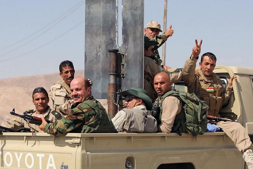 Iraqi Kurdish Peshmerga fighters celebrate sitting on the back of a truck as they head to the Mosul dam on the Tigris river that they recaptured from Islamic State jihadists on Aug 17, 2014 near the northern Iraqi city of Mosul. -- PHOTO: AFP