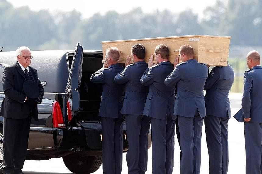 Men carry a coffin containing human remains collected at the crash site of Malaysia Airlines flight MH17 in Ukraine, upon its arrival on Aug 4, 2014 at the Eindhoven Airport, the Netherlands. -- PHOTO: AFP