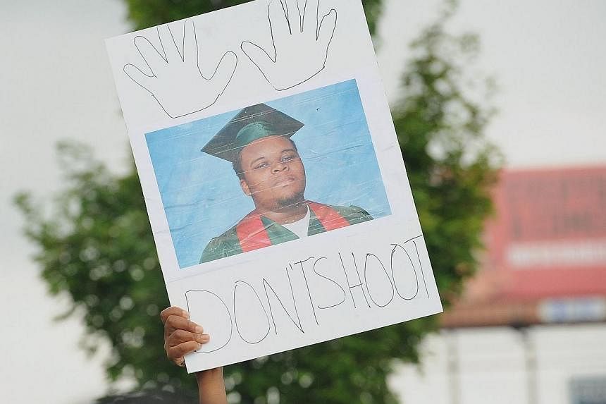 A protestor holds a sign of Michael Brown at a rally in Ferguson, Missouri.&nbsp;A private autopsy report shows that the black teenager killed by a police officer in the suburban St Louis city of Ferguson was shot at least six times, the New York Tim